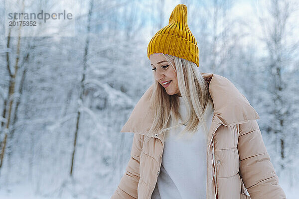 Lächelnde Frau mit Winterjacke im Wald