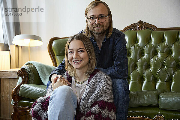 Lächelnde Frau und Mann sitzen zu Hause auf dem Sofa