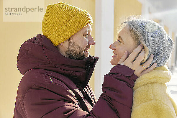 Glücklicher Mann umarmt Frau im Winter an einem sonnigen Tag