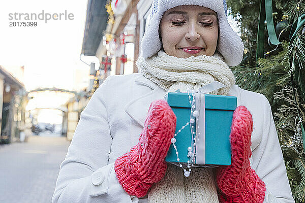 Frau betrachtet dekorierte Geschenkbox zu Weihnachten