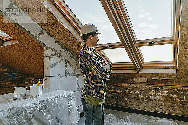 Architekt mit verschränkten Armen steht am Fenster