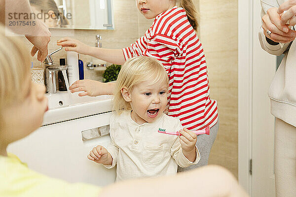 Mädchen putzt Zähne mit Familie im Badezimmer zu Hause