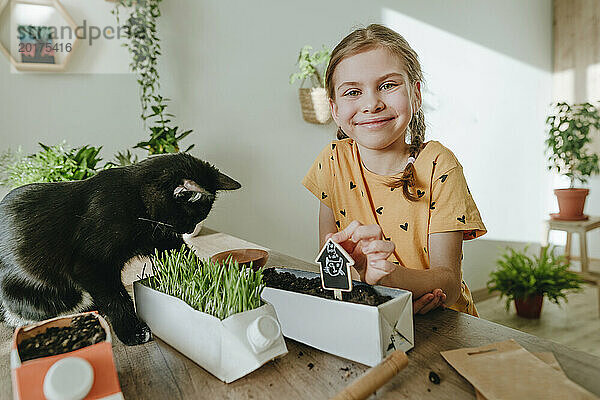 Lächelndes Mädchen pflanzt zu Hause Katzenminze für die Katze