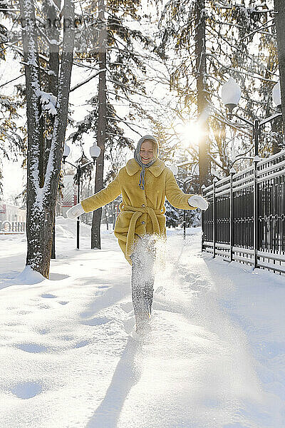 Fröhliche Frau genießt den Schnee im Winterwald