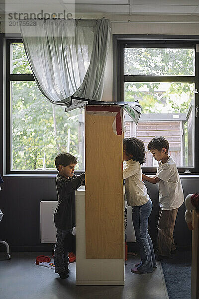 Seitenansicht von Vorschulkindern  die zusammen in der Nähe der Kabine im Klassenzimmer des Kindergartens spielen
