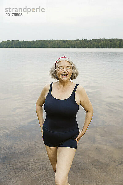 Glückliche ältere Frau im Ruhestand in Badebekleidung  die am Fluss steht