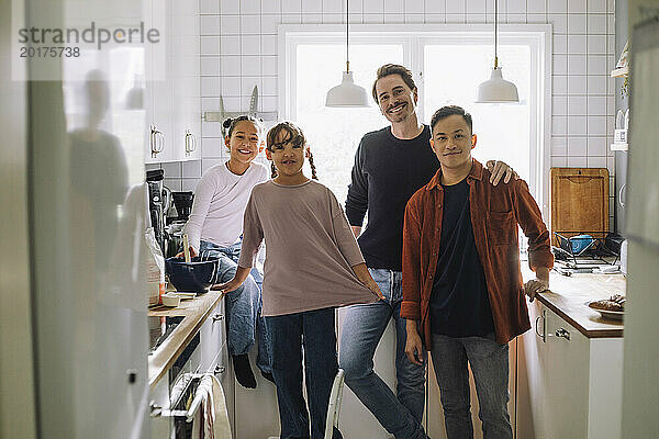 Porträt glücklicher schwuler Männer  die mit ihren Töchtern zu Hause in der Küche stehen