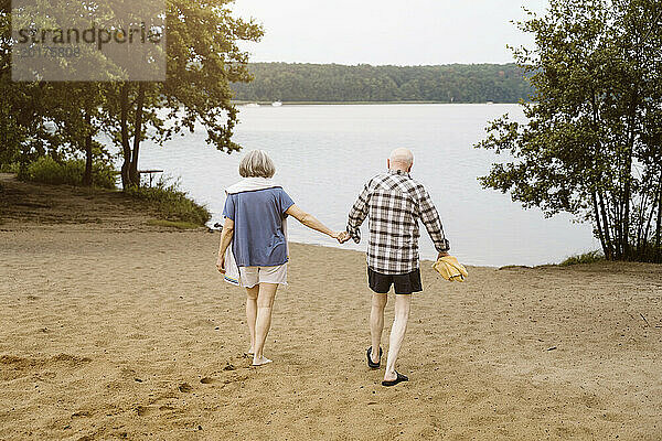 In voller Länge ein älteres Paar  das Händchen hält  während es in Richtung Fluss geht
