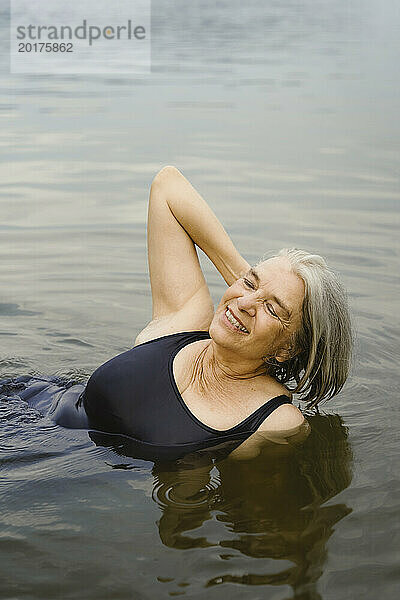 Glückliche ältere Frau schwimmt im Fluss
