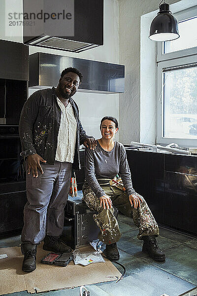 Porträt glücklicher männlicher und weiblicher Tischler  die in der Küche einer Wohnung sitzen