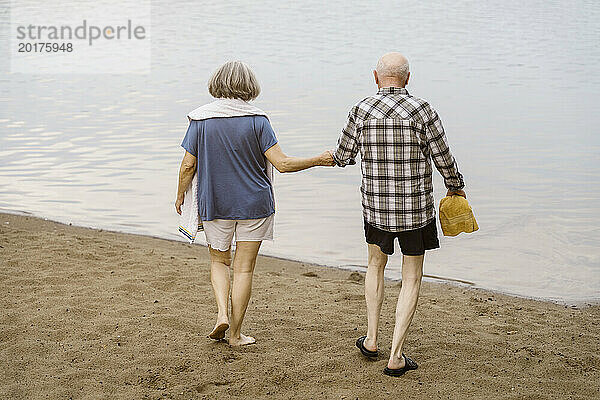 Rückansicht eines älteren Paares  das Händchen hält  während es in Richtung Fluss geht