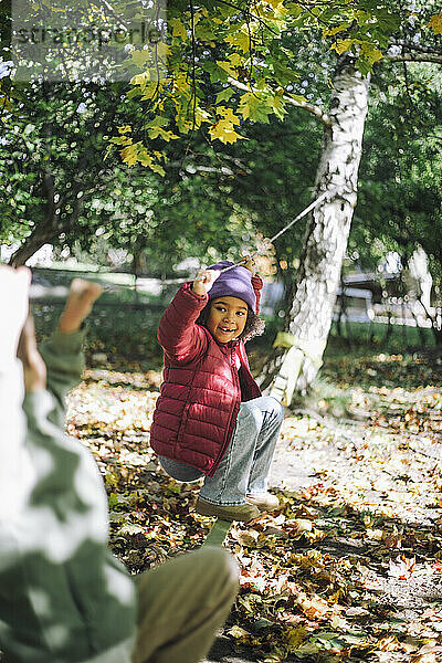 Verspieltes Mädchen hängt am Seil  während es im Park spielt