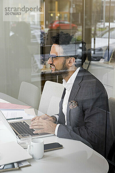 Seitenansicht eines männlichen Immobilienmaklers mit Laptop im Büro