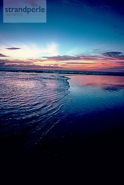 Indonesien. Bali. Strandsonnenuntergang über dem Rand des Wassers.