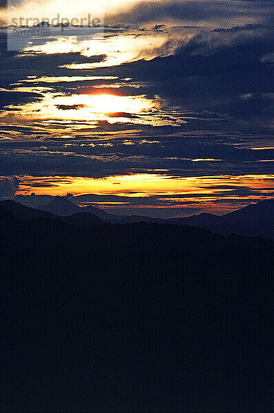 Papua Neu-Guinea. Südliches Hochland. Stürmischer Sonnenuntergang über den Bergen.