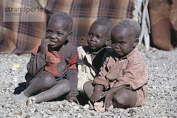 Namibia. Dorf des Himba-Stammes. Kinder sitzen draußen.