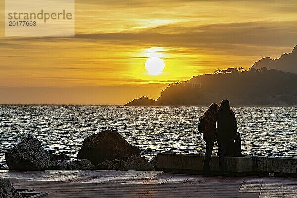 Silhouette eines Paares  das den Sonnenuntergang am Meer auf einer Promenade genießt  Peguera  Mallorca