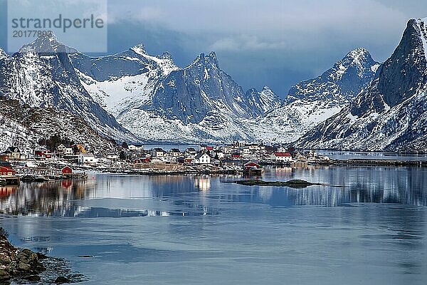 Friedlicher Fjord mit Fischerdorf  schneebedeckte Berge spiegeln sich im ruhigen Wasser  Lofoten