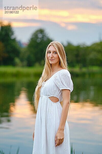 Hübsche Frau am Fluss in der Abenddämmerung