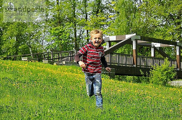 Ein fröhlicher Junge rennt über eine Sommerwiese. A happy boy runs through a summer meadow