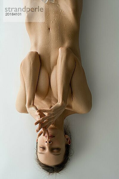 Draufsicht auf schlankes weibliches Modell mit Wassertropfen auf nacktem Körper bedecken Brust mit Händen