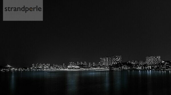 Eine ruhige Schwarz Weiß Nachtaufnahme der Stadtsilhouette mit Reflexionen auf dem Wasser  in Südkorea