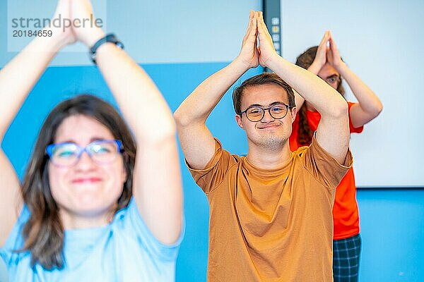 Glückliche Gruppe behinderter Menschen  die ihre Arme beim Yoga in der Turnhalle heben