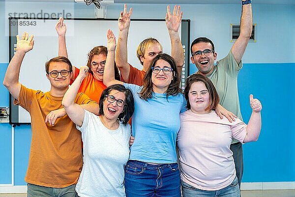 Glückliche Menschen mit besonderen Bedürfnissen posieren nach dem Gymnastikunterricht und lachen in die Kamera und heben die Hände