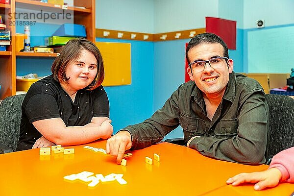 Zwei Menschen mit besonderen Bedürfnissen spielen abgelenkt Brettspiele an einem Tisch in einem Tageszentrum