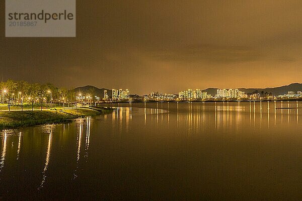 Nachtszene eines Parks am Seeufer in Südkorea mit sich im Wasser spiegelnden Lichtern der Stadt Sejeong  Südkorea  Asien