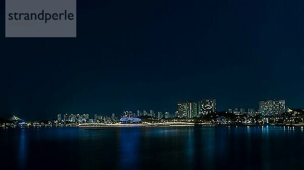 Nachtszene eines Parks am Seeufer in Südkorea mit sich im Wasser spiegelnden Lichtern der Stadt Sejeong  Südkorea  Asien