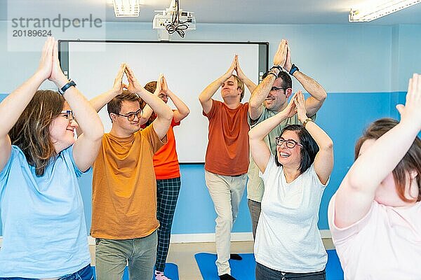 Glückliche behinderte Menschen haben Spaß beim gemeinsamen Yogaunterricht in einer Turnhalle