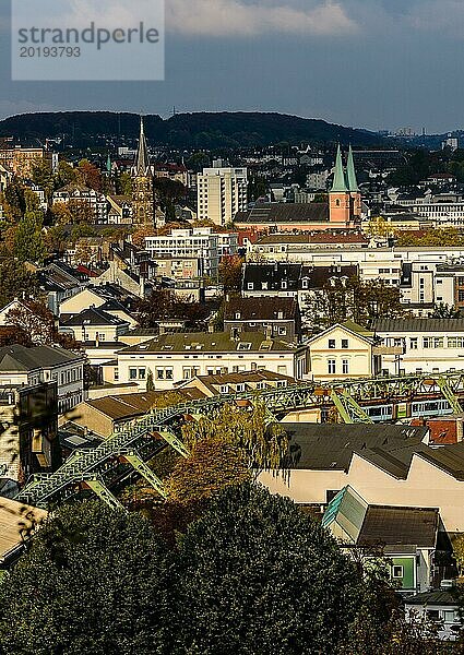 Blick auf eine Stadt mit verschiedenen Gebäuden und Kirchtürmen  umgeben von herbstlichen Bäumen  Schwebebahn  Arrenberg  Elberfeld  Wuppertal  Nordrhein-Westfalen