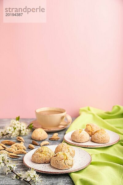 Mandelkekse und eine Tasse Kaffee auf grauem und rosa Hintergrund und grünem Leinenstoff. Seitenansicht  Nahaufnahme  selektiver Fokus  Kopierraum