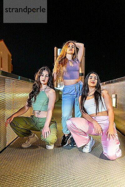 Vertikales Porträt von drei schönen Hip Hop Tänzern  die nachts in der Stadt zusammen posieren
