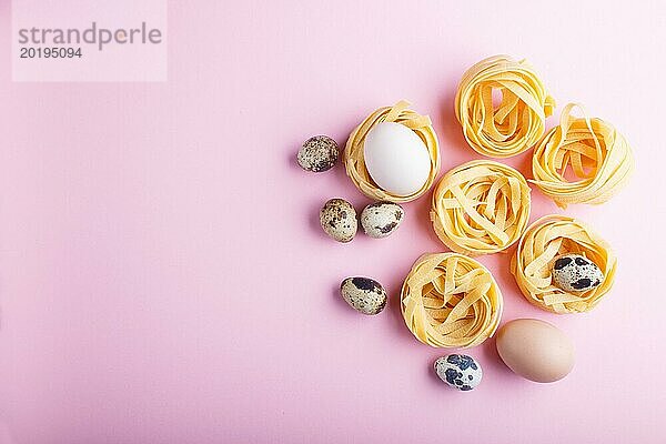 Rohe ungekochte Tagliatelle Nudeln mit Wachteleiern auf einem rosa pastellfarbenen Hintergrund. Ansicht von oben  Kopierbereich