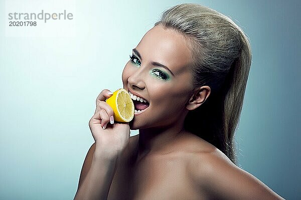 Schöne junge Frau lächeln und schmecken Zitrone