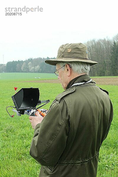 Jäger beobachtet fliegende Drohne auf dem Bildschirm des Steuergerätes anlässlich einer Feldhasen (Lepus europaeus) Zählung  Niederösterreich  Österreich  Europa