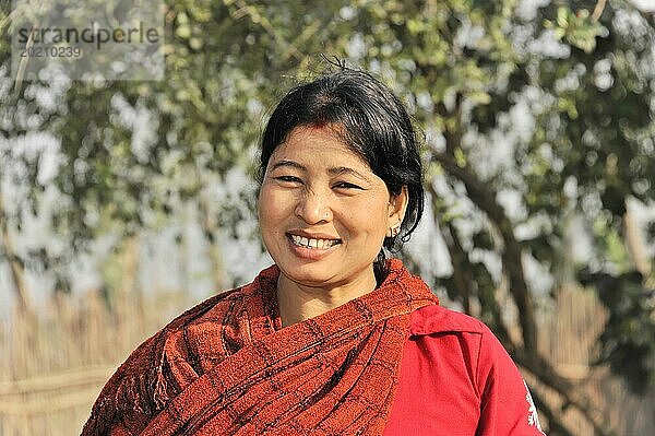 Freundlich lächelnde Frau mit einem roten Schal im Freien an einem sonnigen Tag  Chitwan Nationalpark  Nepal  Asien