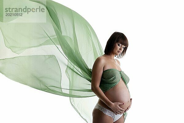 Schöne schwangere Frau mit grünem wehenden Stoff. vor weißem Hintergrund
