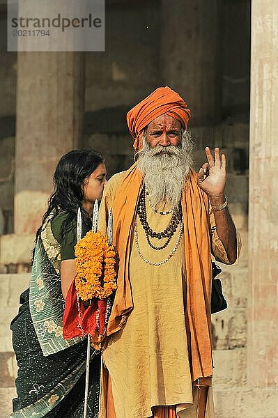 Mann in orange-farbener traditioneller Kleidung segnet Frau mit Blumenkranz  Varanasi  Uttar Pradesh  Indien  Asien