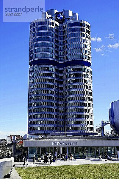 Das BMW-Gebäude mit seiner prägnanten Form und Menschen davor an einem sonnigen Tag  BMW WELT  München  Deutschland  Europa