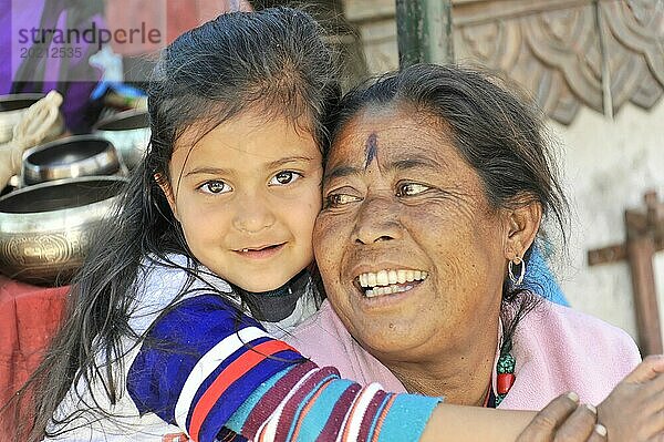 Eine Großmutter umarmt ihre Enkelin liebevoll und beide lächeln glücklich  Kathmandu-Tal  Kathmandu  Nepal  Asien