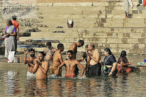 Personen bei rituellen Waschungen im Fluss unter der wärmenden Morgensonne  Varanasi  Uttar Pradesh  Indien  Asien