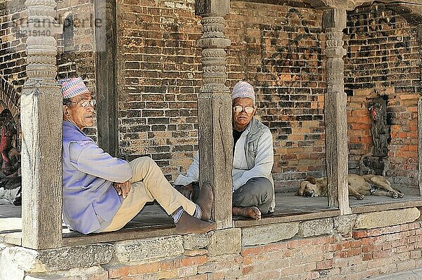 Zwei ältere Männer in traditioneller Kleidung entspannen sich in einer alten Holzstruktur  Kathmandu-Tal. Kathmandu  Nepal  Asien