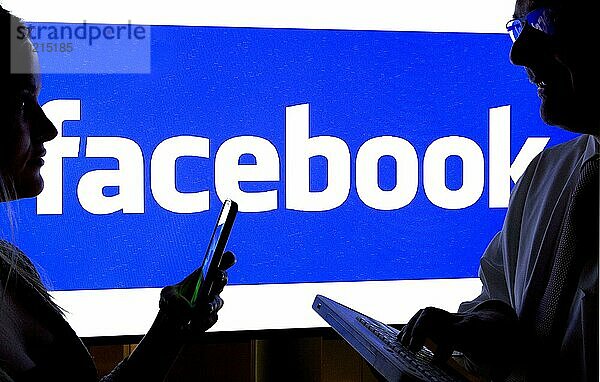 Frau und ein Mann mit Smartphones vor Facebook Logo  12.01.2016