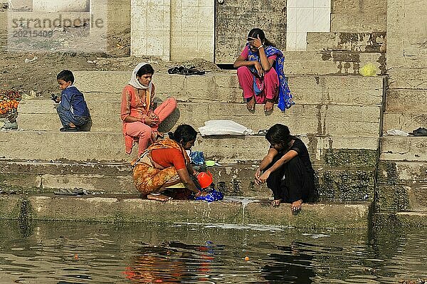 Drei Frauen in traditioneller Kleidung  die an den Ghats sitzen und sich unterhalten  Varanasi  Uttar Pradesh  Indien  Asien