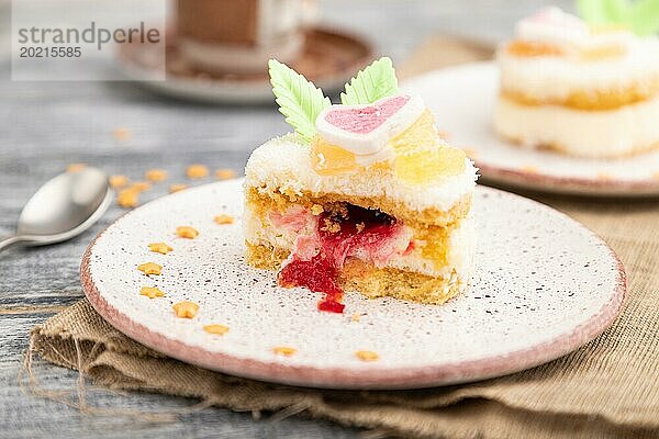 Dekorierter Kuchen mit Milch und Kokosnusscreme mit einer Tasse Kaffee auf einem grauen Holzhintergrund und Leinenstoff. Seitenansicht  Nahaufnahme  selektiver Fokus