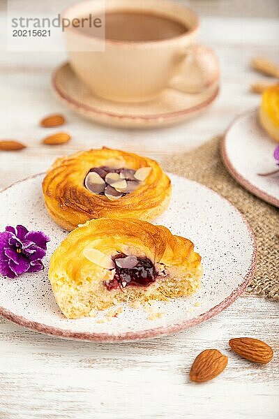 Kleine Käsekuchen mit Marmelade und Mandeln mit einer Tasse Kaffee auf einem weißen Holzhintergrund und Leinenstoff. Seitenansicht  Nahaufnahme  selektiver Fokus