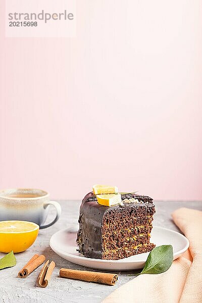 Hausgemachter Schokoladenkuchen mit Orange und Zimt mit einer Tasse Kaffee auf grauem und rosa Hintergrund mit orangefarbenem Textil. Seitenansicht  selektiver Fokus  Kopierbereich